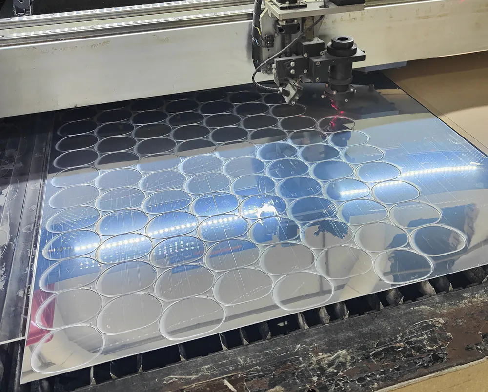 A laser is cutting a large sheet of mirror