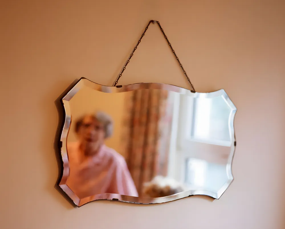 The old man looked at the mirror hanging on the wall