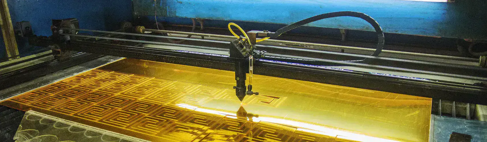 A laser cutter is cutting a gold-colored plastic mirror