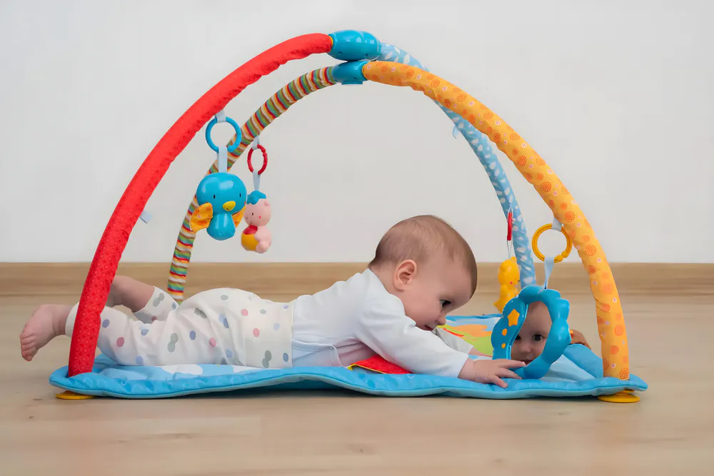 Baby captivated by the mirror in the baby gym